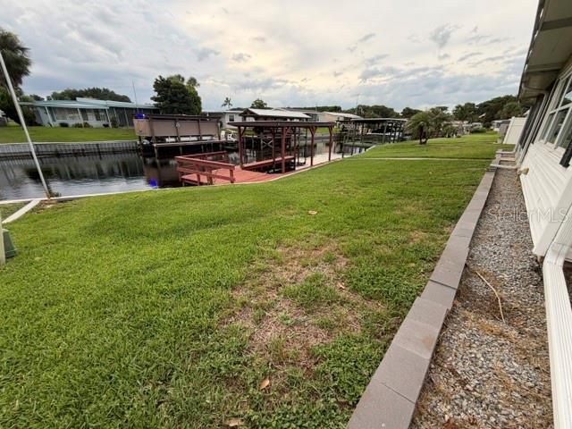 A grassy backyard leads to a canal with several boat docks and covered boat lifts — 1023 SOUTHLAND DRIVE, TAVARES, FL