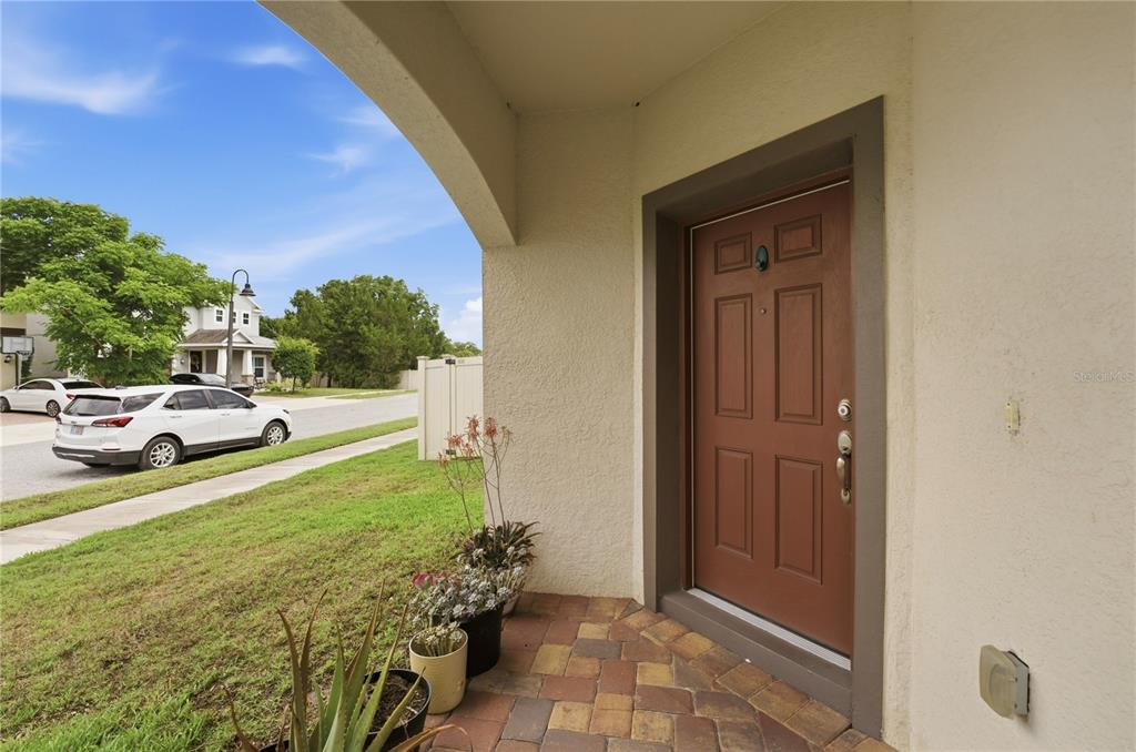 A covered entryway features a brown front door, brick pavers, and potted plants — 5248 LANDMARK DRIVE, ST CLOUD, FL