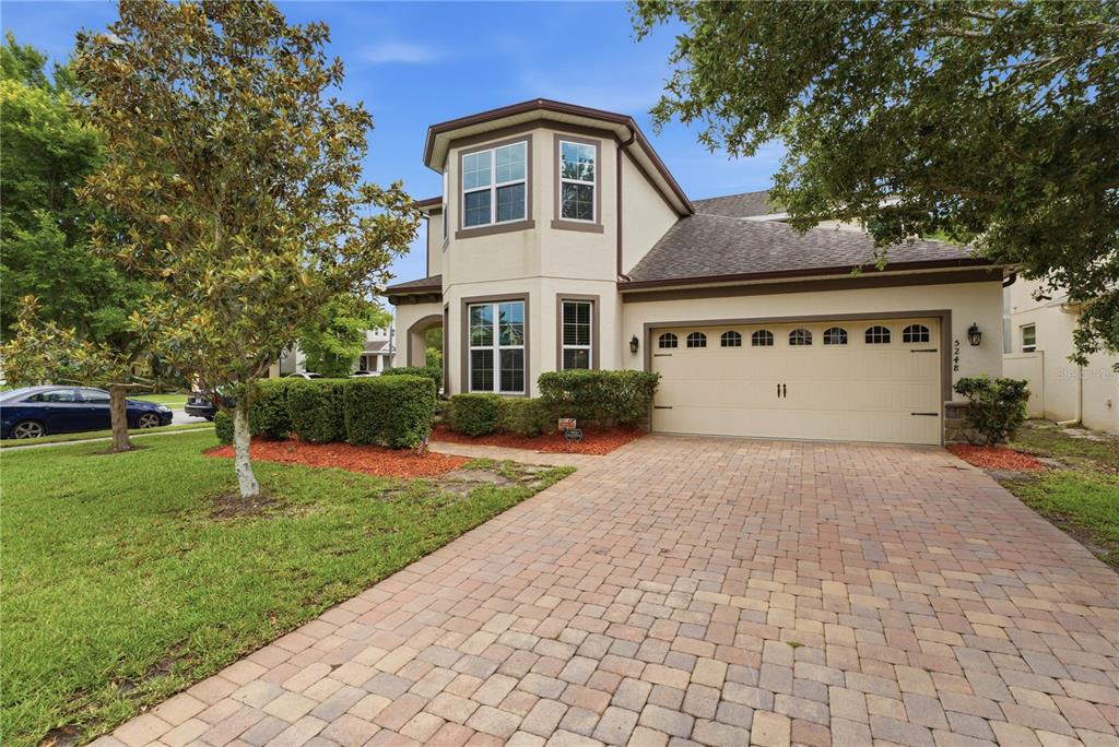 A two-story house with a beige stucco exterior, a paved driveway, and a two-car garage — 5248 LANDMARK DRIVE, ST CLOUD, FL
