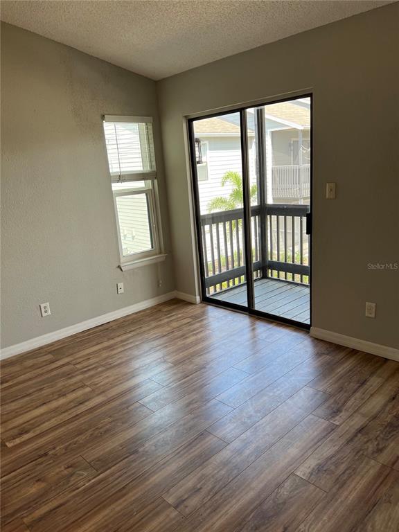An empty room with wood-look flooring, a single window, and a sliding glass door to a balcony — 3740 IDLEBROOK CIRCLE UNIT 202, CASSELBERRY, FL