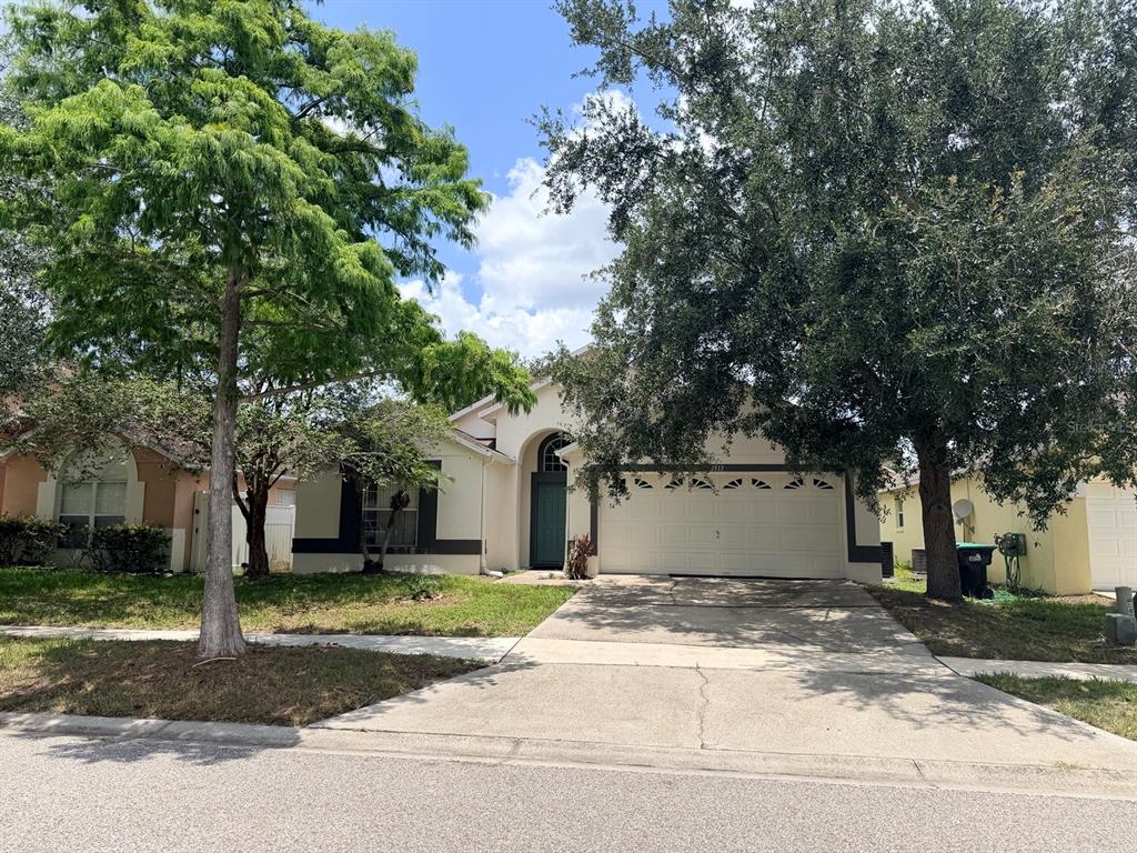 A single-story house with a two-car garage, a green front door, and large shade trees — 3513 MCALLISTER WAY, ORLANDO, FL