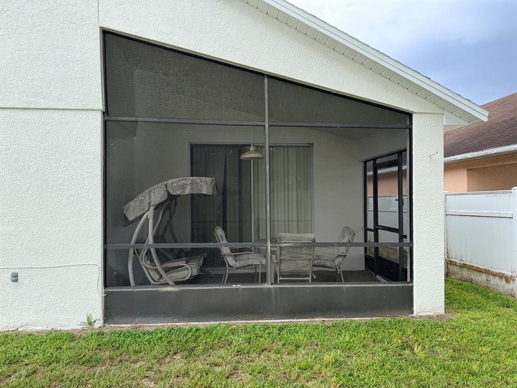 A screened-in patio with a metal frame sits against the side of a stucco house — 3513 MCALLISTER WAY, ORLANDO, FL