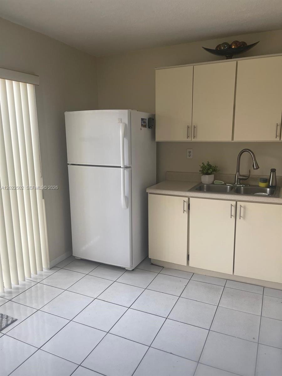 A kitchen features a white refrigerator, light-colored cabinets, a stainless steel sink, and tile flooring — 9880 Hammocks Blvd # 43, Miami FL 33196, MIAMI, FL