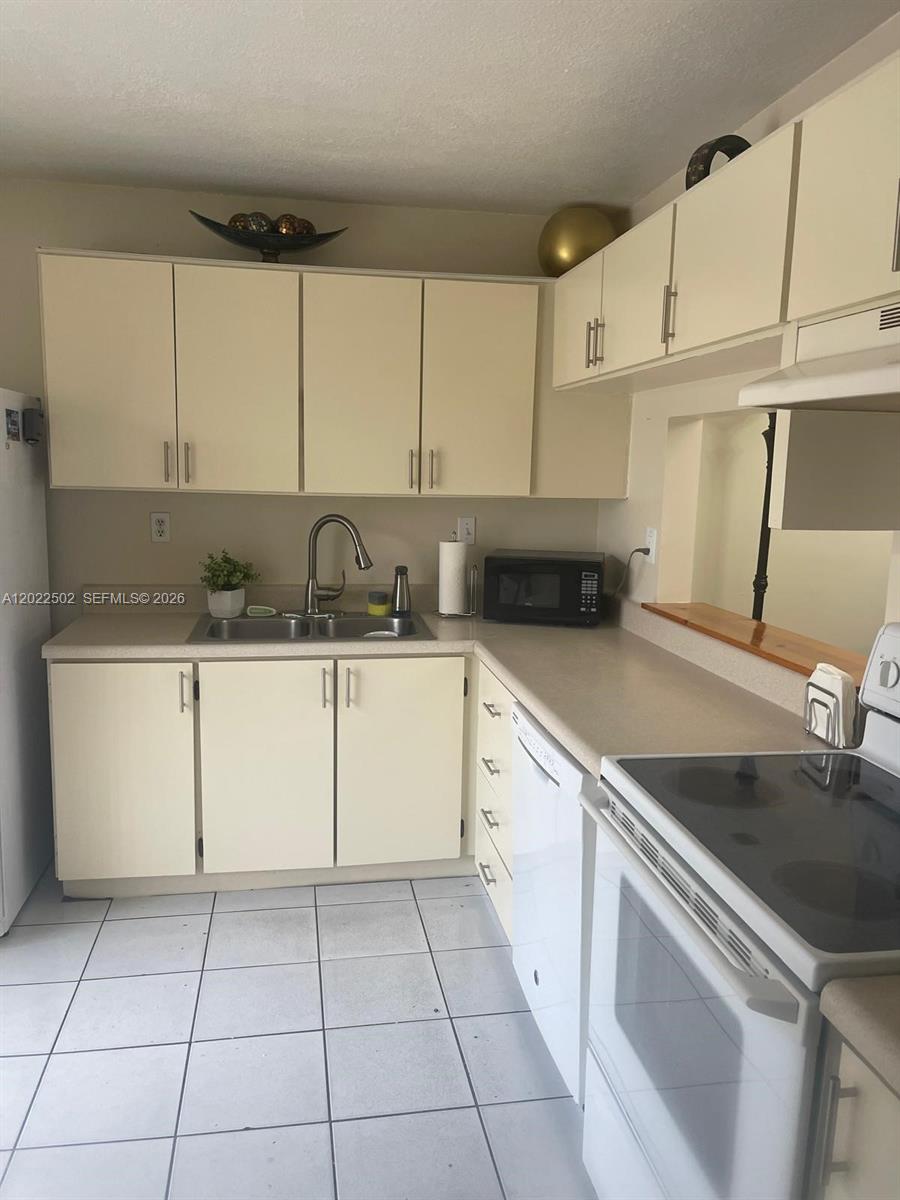 A kitchen features off-white cabinets, a double sink, white appliances, and light-colored tile flooring — 9880 Hammocks Blvd # 43, Miami FL 33196, MIAMI, FL