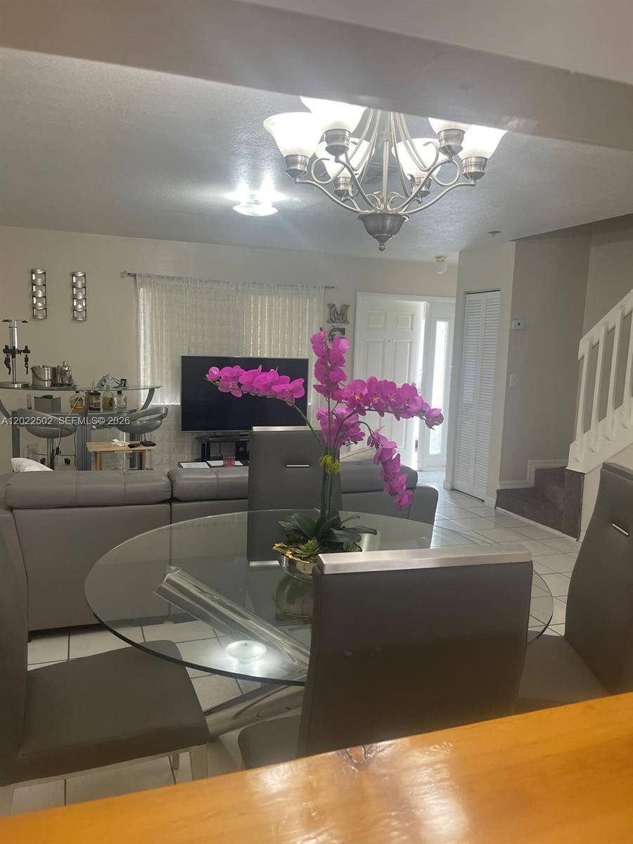 A dining area with a glass table and orchid centerpiece overlooks a living room — 9880 Hammocks Blvd # 43, Miami FL 33196, MIAMI, FL