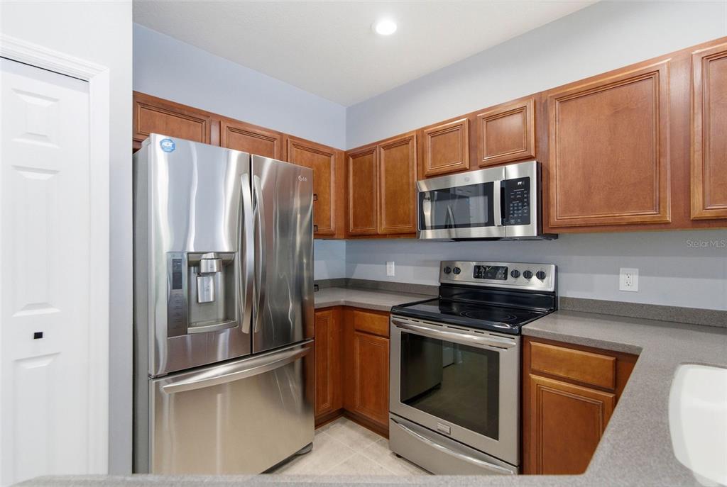 A kitchen features stainless steel appliances, wood cabinets, and gray countertops — 20402 NEEDLETREE DRIVE, TAMPA, FL