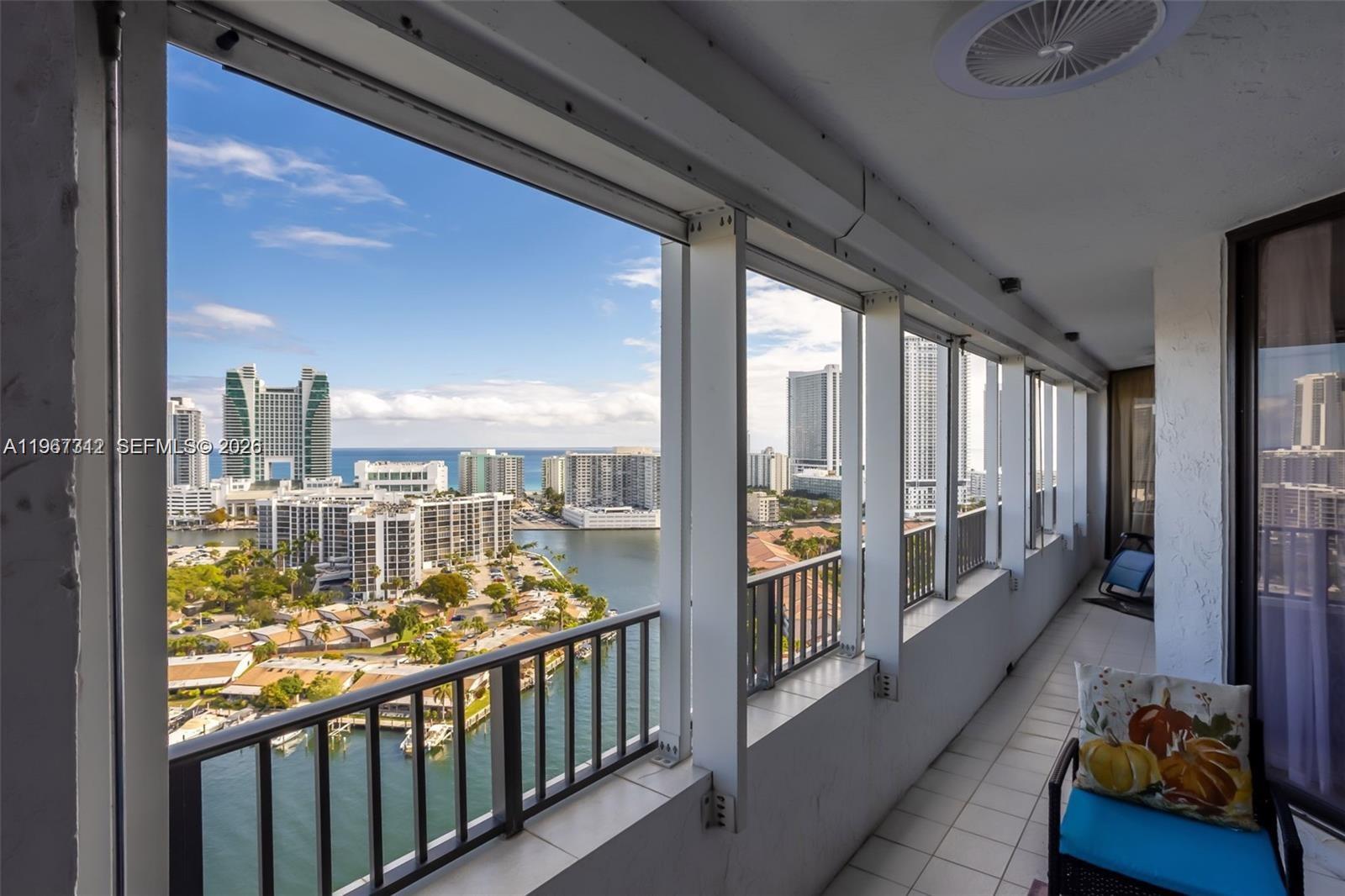 A balcony with white tile flooring overlooks a coastal city and a waterway — 300 Three Islands Blvd, Hallandale Beach FL 33009, HALLANDALE BEACH, FL