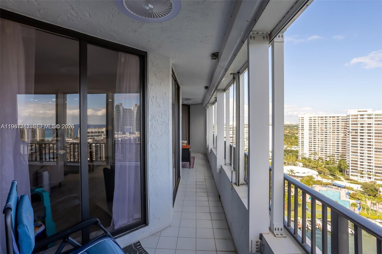 A long, tiled balcony features sliding glass doors, white support columns, and a metal railing — 300 Three Islands Blvd, Hallandale Beach FL 33009, HALLANDALE BEACH, FL