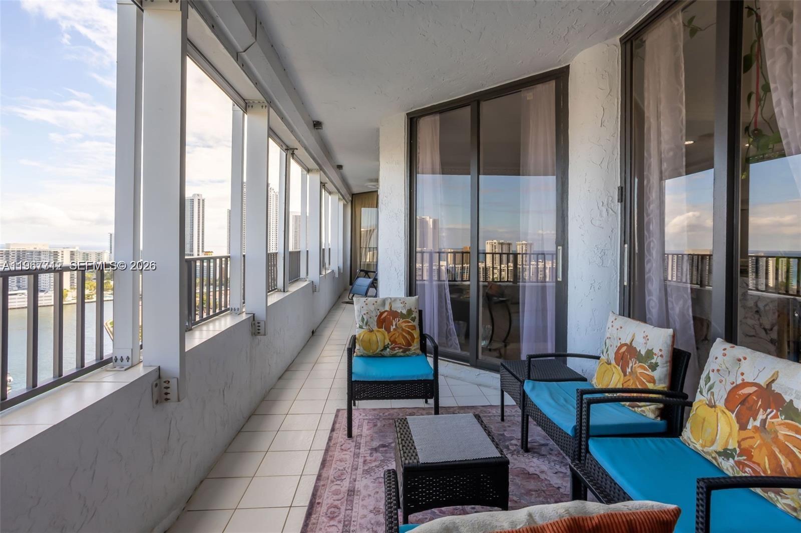 A balcony with tiled flooring, outdoor furniture, and a view of high-rise buildings — 300 Three Islands Blvd, Hallandale Beach FL 33009, HALLANDALE BEACH, FL
