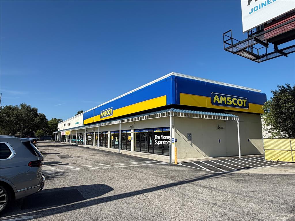 An exterior view of a commercial building with Amscot signage and a parking lot — 2910 N HIMES AVENUE UNIT 2922, TAMPA, FL