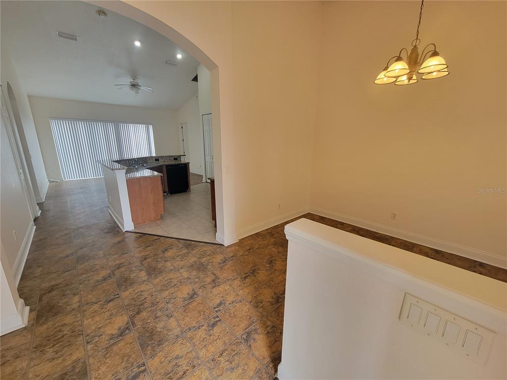 A dining area with a chandelier leads through an arched opening to a kitchen — 13092 SW 84TH TERRACE ROAD, OCALA, FL