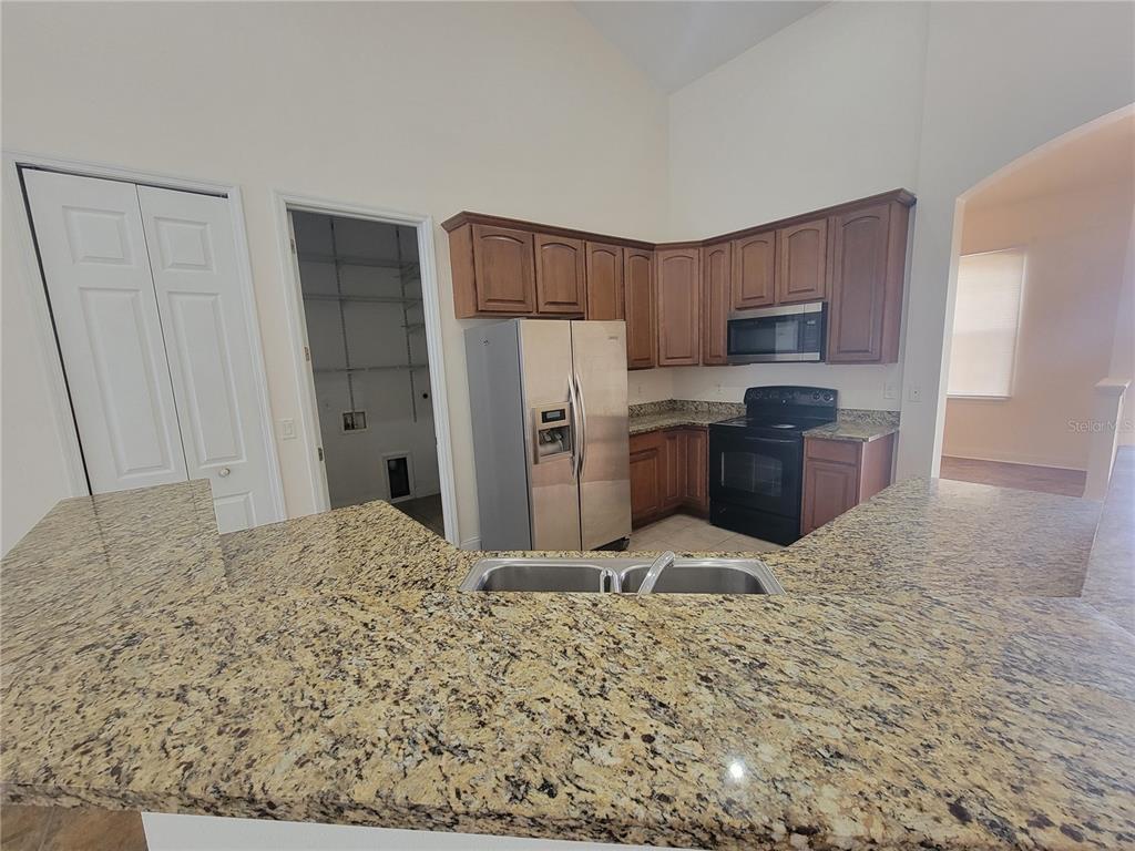 A kitchen features wood cabinets, granite countertops, stainless steel appliances, and a double sink — 13092 SW 84TH TERRACE ROAD, OCALA, FL