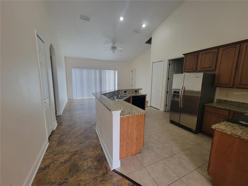 A kitchen with granite countertops and stainless steel appliances opens to a living area — 13092 SW 84TH TERRACE ROAD, OCALA, FL