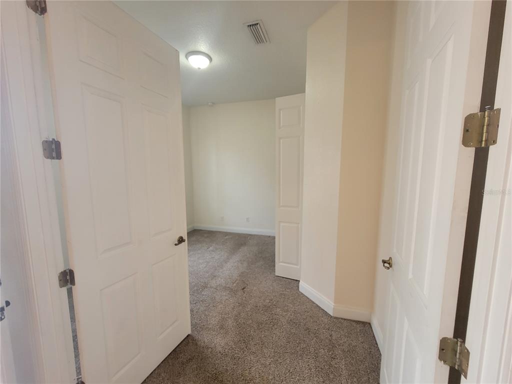 A view through an open doorway into a carpeted room with beige walls — 13092 SW 84TH TERRACE ROAD, OCALA, FL