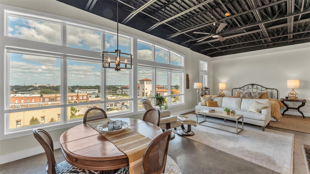 A studio apartment with a dining area, living space, bed, and large windows overlooking a city — 125 N KENTUCKY AVENUE UNIT 505, LAKELAND, FL