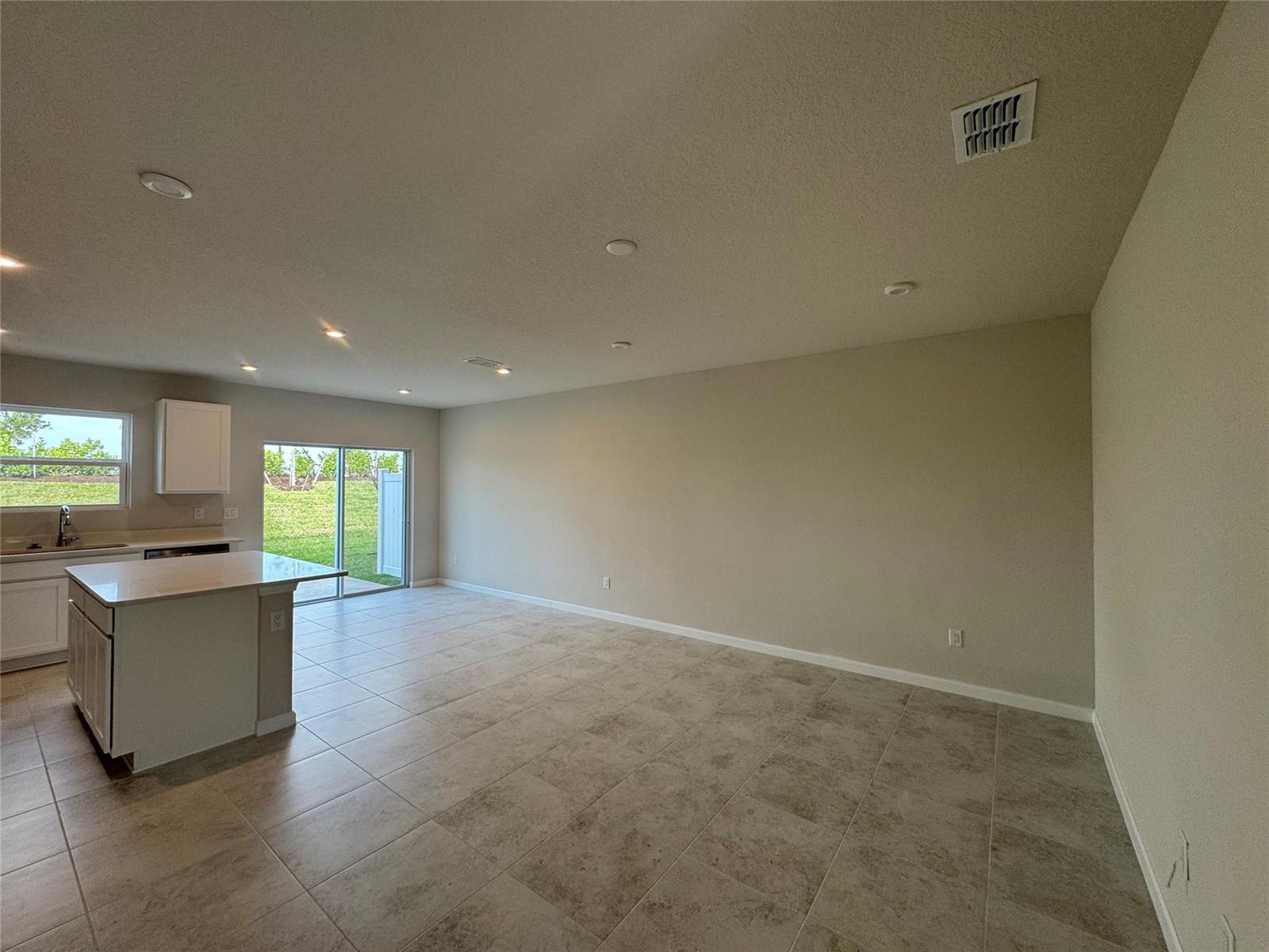 An open-concept kitchen and living area features tile flooring, recessed lighting, and a sliding door — PORT ST. LUCIE, FL