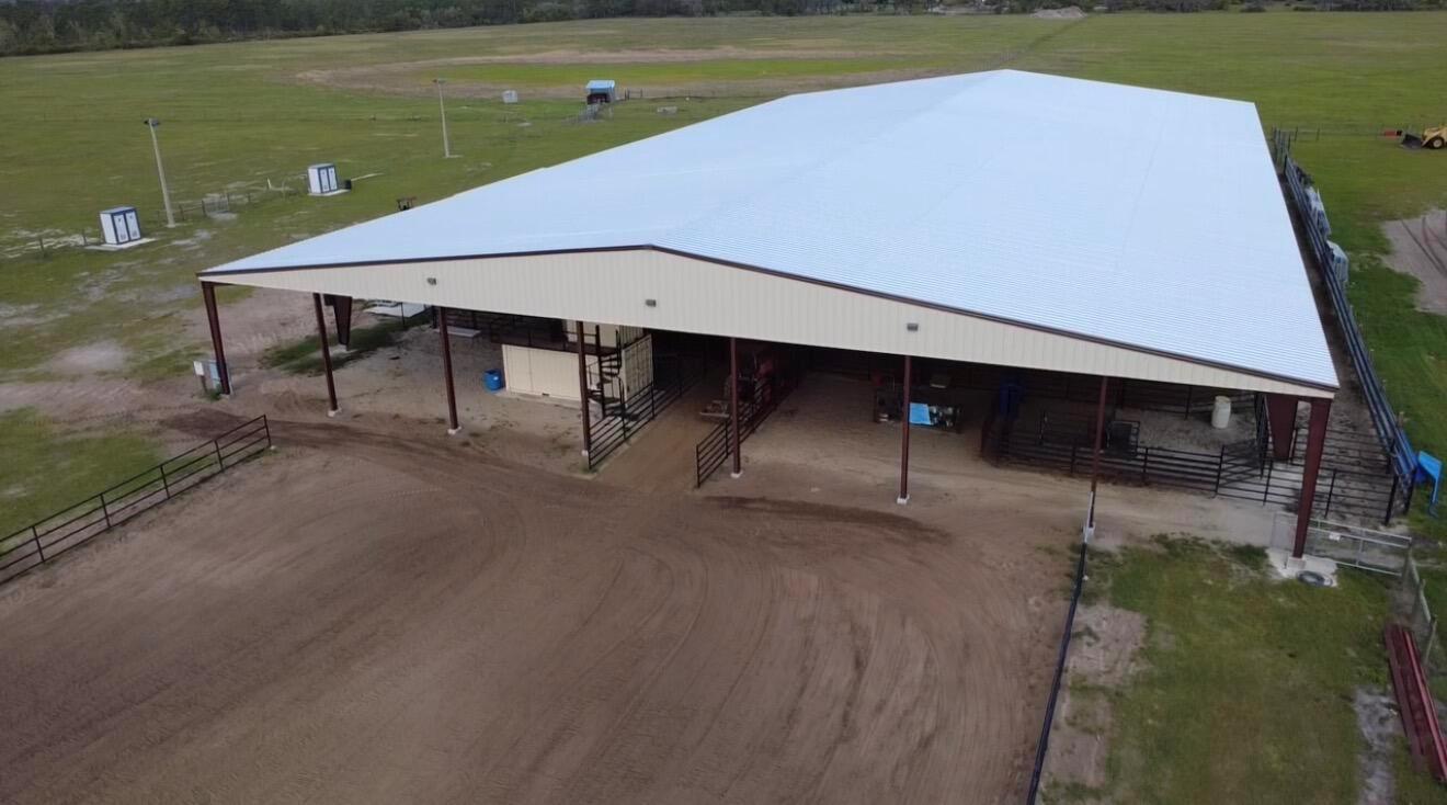 An aerial view of a large, open-air metal barn structure situated on a grassy field — 33700 Hwy 441, Okeechobee FL 34972, OKEECHOBEE, FL