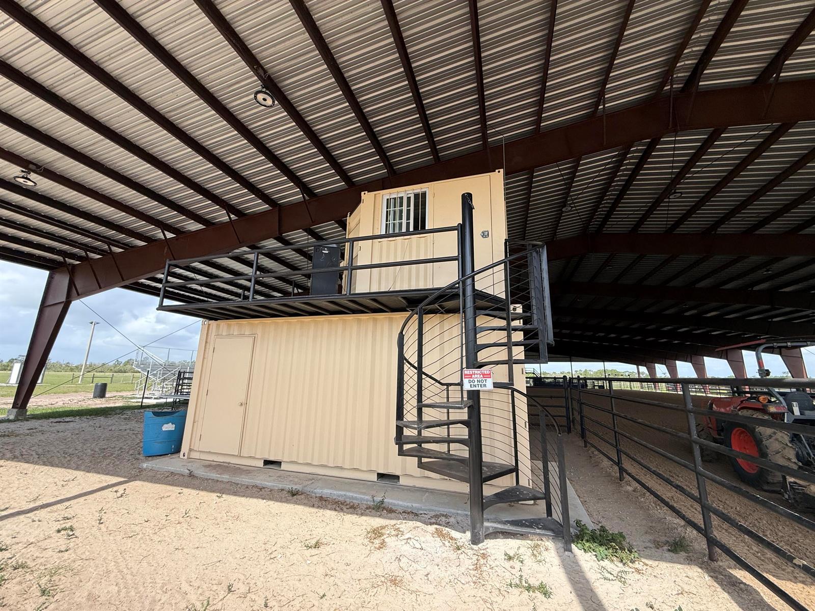 A two-story shipping container structure with a spiral staircase sits under a large metal roof — 33700 Hwy 441, Okeechobee FL 34972, OKEECHOBEE, FL