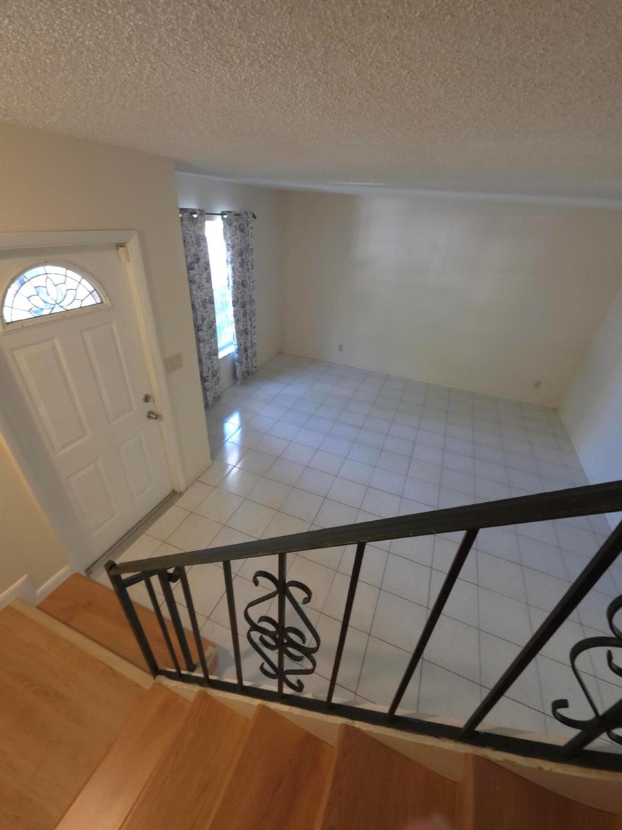 A view from a staircase looking down at a tiled entryway with a front door — HALLANDALE BEACH, FL