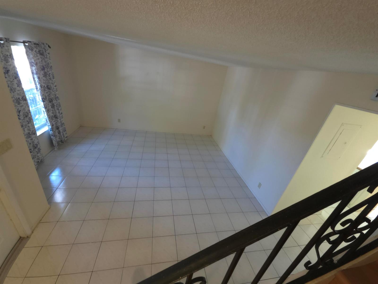 An empty room with white tile flooring and a slanted ceiling viewed from above — HALLANDALE BEACH, FL