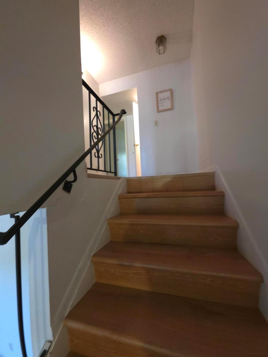 A wooden staircase with a black metal railing leads to an upper landing — HALLANDALE BEACH, FL