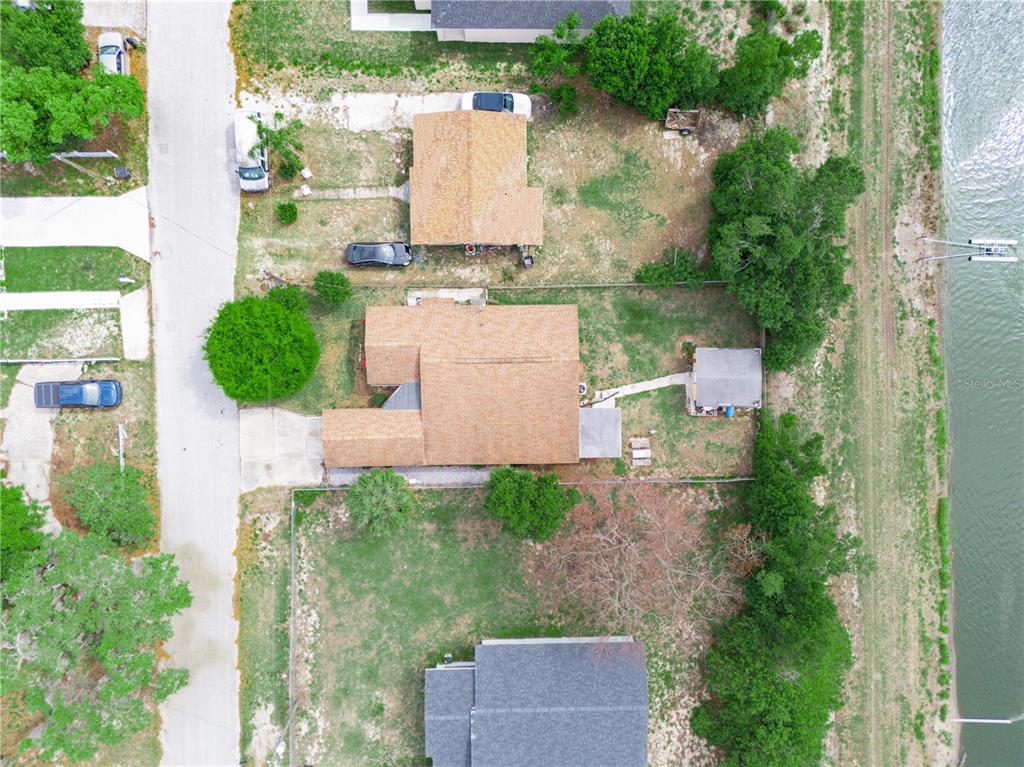 An aerial view shows three houses along a road with a canal in the background — 129 W NORTHSIDE DRIVE, LAKE WALES, FL