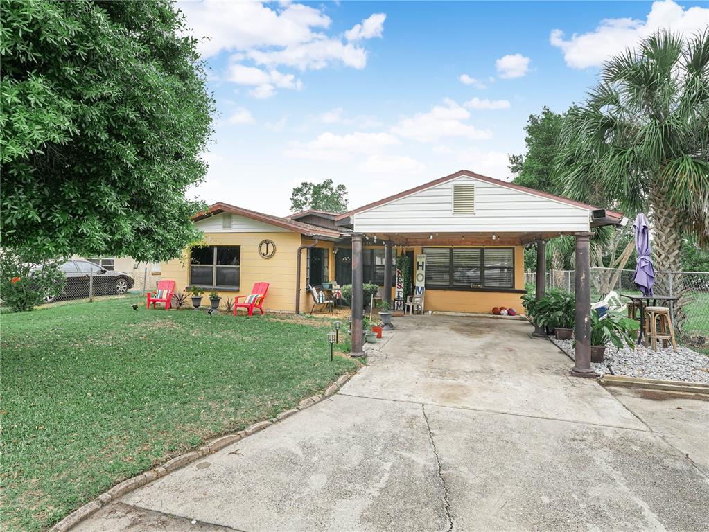 A yellow single-story house features a concrete driveway, a covered carport, and a front lawn — 129 W NORTHSIDE DRIVE, LAKE WALES, FL