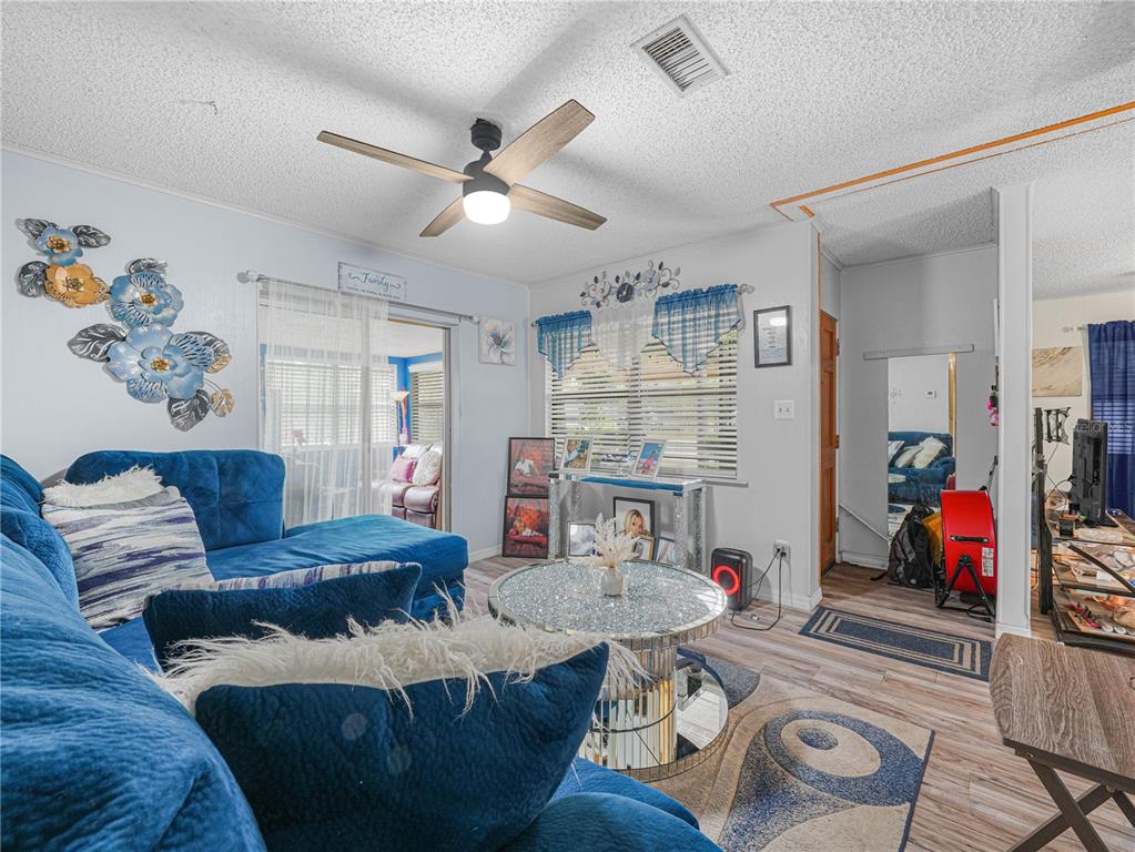A living room features a blue sectional sofa, a mirrored coffee table, and wood-look flooring — 129 W NORTHSIDE DRIVE, LAKE WALES, FL