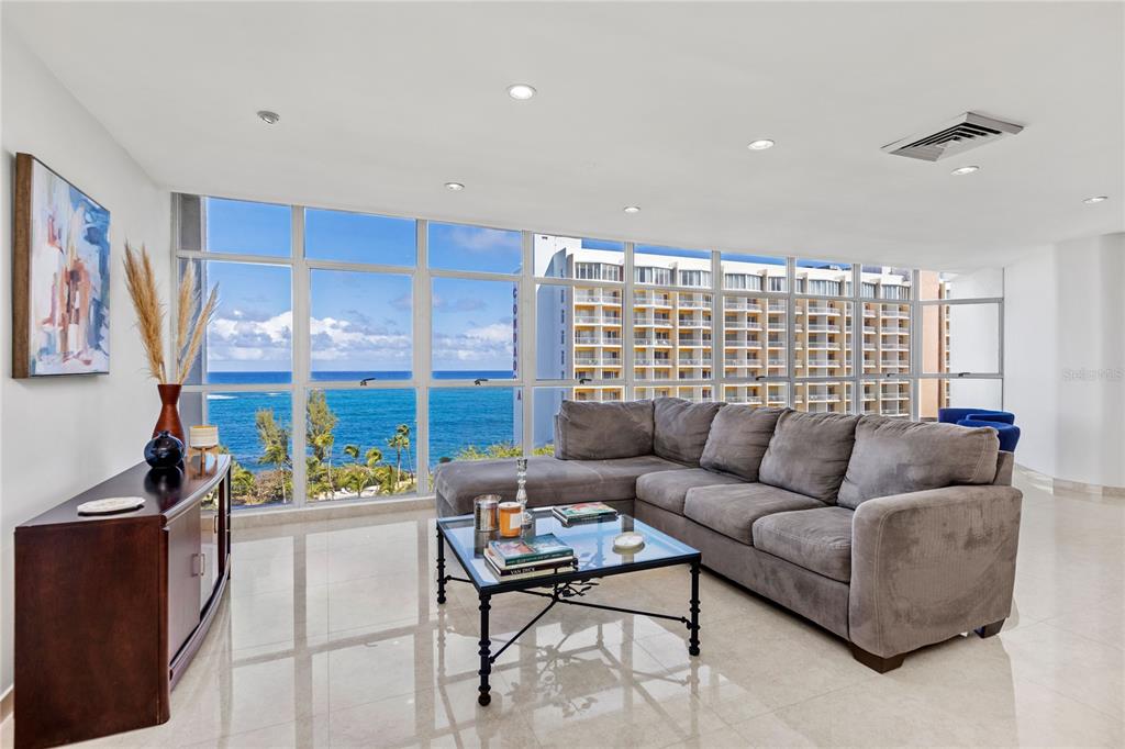 A living room features a gray sectional sofa, glass coffee table, and floor-to-ceiling ocean views — 860 ASHFORD AVE UNIT 9, SAN JUAN, PR