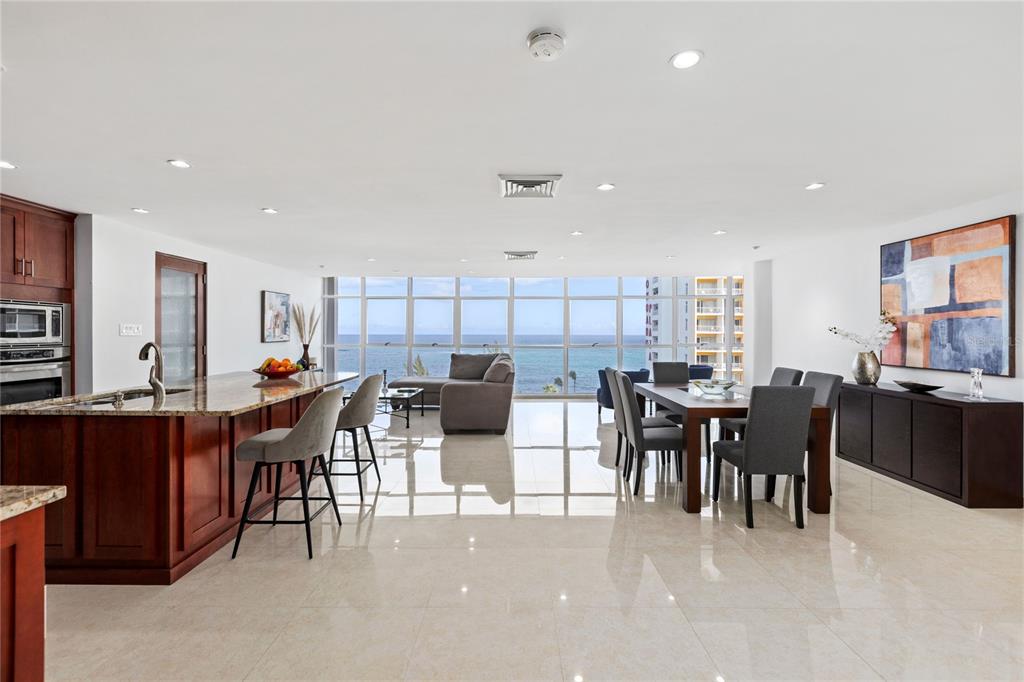 An open-concept kitchen and dining area features tile floors, dark wood cabinetry, and ocean views — 860 ASHFORD AVE UNIT 9, SAN JUAN, PR