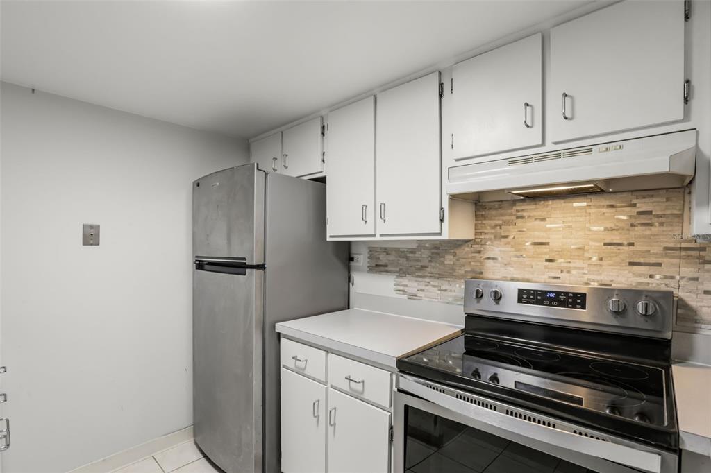 A kitchen features white cabinets, stainless steel appliances, and a tiled backsplash — 200 MAITLAND AVENUE UNIT 20, ALTAMONTE SPRINGS, FL