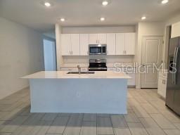A spacious, empty room features light-colored tile flooring, white walls, a ceiling fan, and windows — 12588 TIMBER MOSS LANE, RIVERVIEW, FL