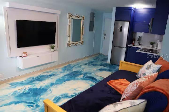 A studio apartment features a blue ocean-themed epoxy floor, a kitchenette, and a wall-mounted television — 1126 ASHFORD UNIT 27, SAN JUAN, PR