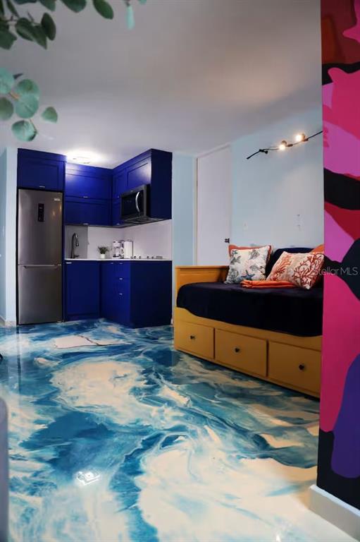 A studio apartment features blue kitchen cabinets, a daybed, and a swirling blue epoxy floor — 1126 ASHFORD UNIT 27, SAN JUAN, PR