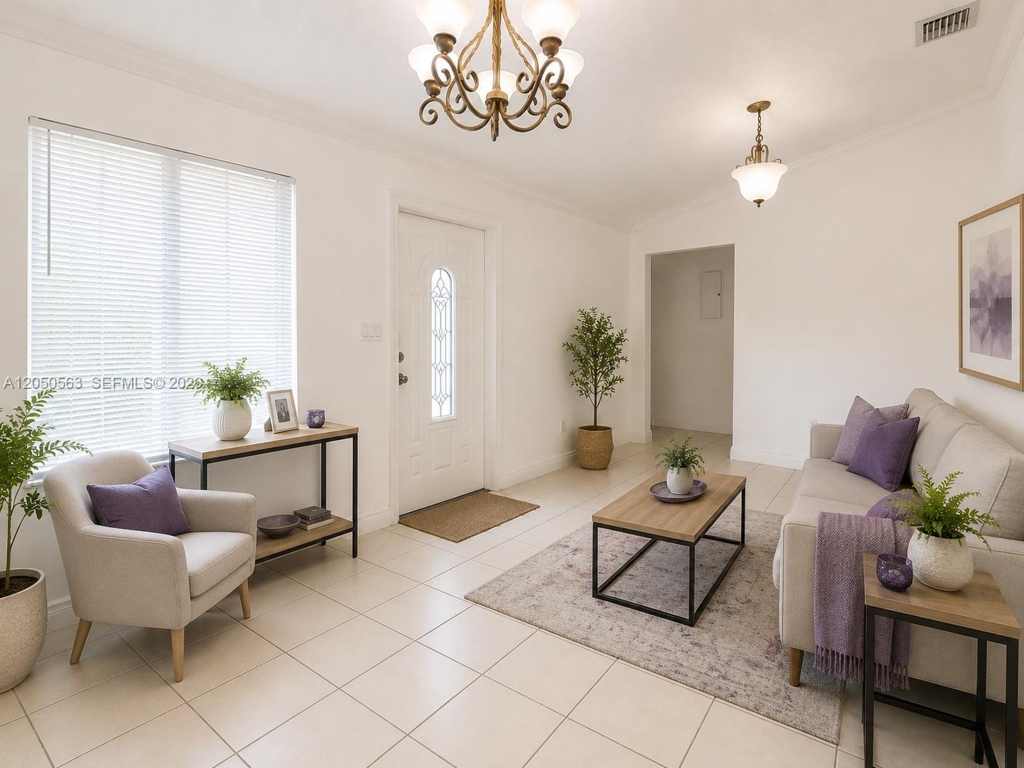 A bright living room features white walls, tile flooring, a chandelier, and neutral-toned furniture — 14326 SW 177th Ter, Miami FL 33177, MIAMI, FL