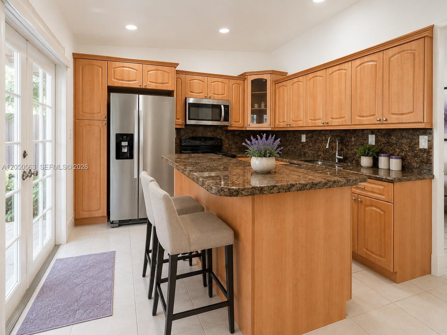 A kitchen features light wood cabinets, granite countertops, stainless steel appliances, and a breakfast bar — 14326 SW 177th Ter, Miami FL 33177, MIAMI, FL