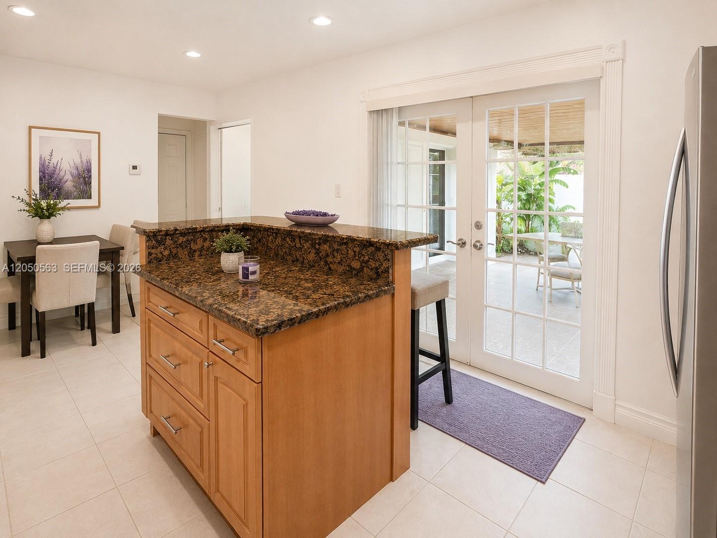 A kitchen island with granite countertops sits before glass doors leading to a patio — 14326 SW 177th Ter, Miami FL 33177, MIAMI, FL