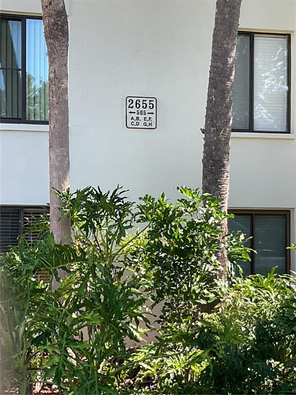 A building exterior features a white wall with a unit number sign and palm trees — 2655 PINE RIDGE WAY N UNIT D3, PALM HARBOR, FL