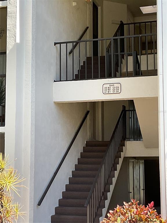 An outdoor staircase leads to a second-floor landing with a unit number directory sign — 2655 PINE RIDGE WAY N UNIT D3, PALM HARBOR, FL