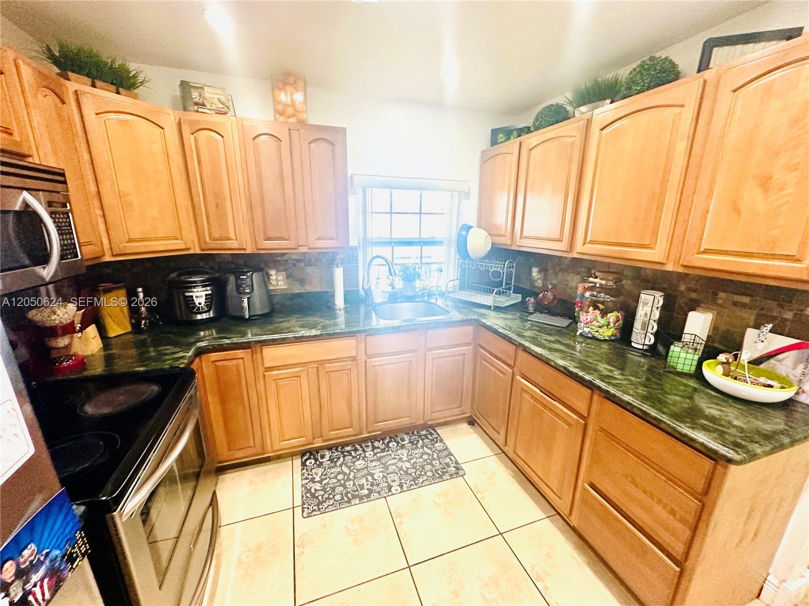 A kitchen features light wood cabinets, green countertops, and a stainless steel stove — 6837 W 19th Ct # 6837, Hialeah FL 33014, HIALEAH, FL