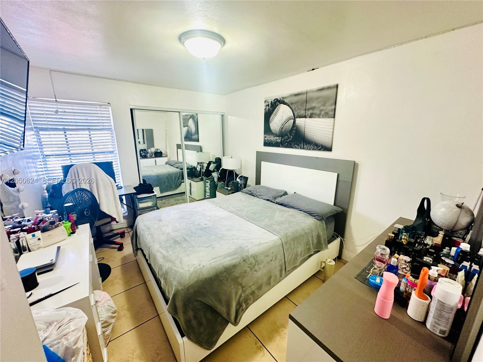 A bedroom features a bed with a gray blanket, a mirrored closet, and tile flooring — 6837 W 19th Ct # 6837, Hialeah FL 33014, HIALEAH, FL