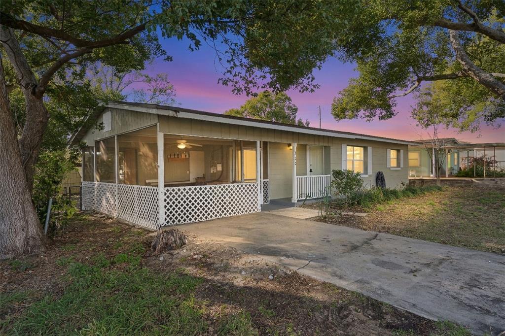 A single-story house with a screened-in front porch, concrete driveway, and mature trees — 902 S GALENA AVENUE, MINNEOLA, FL