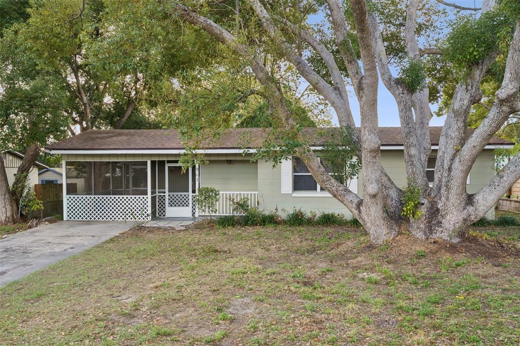 A single-story house with a screened-in porch and a large tree in the front yard — 902 S GALENA AVENUE, MINNEOLA, FL
