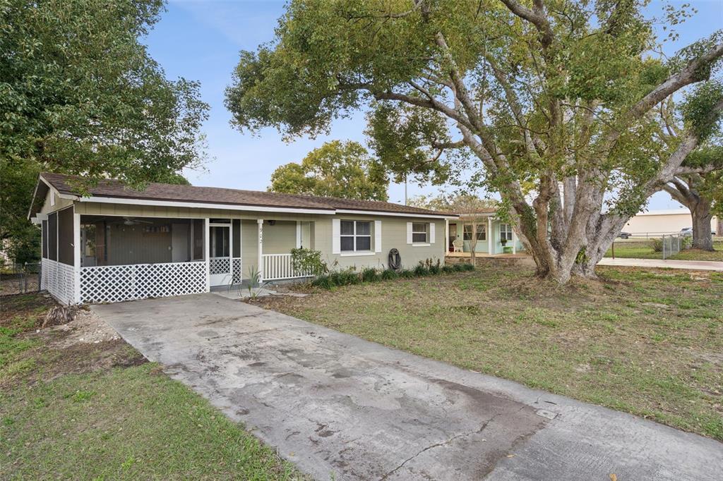 A single-story house with a screened porch, concrete driveway, and large trees in the yard — 902 S GALENA AVENUE, MINNEOLA, FL