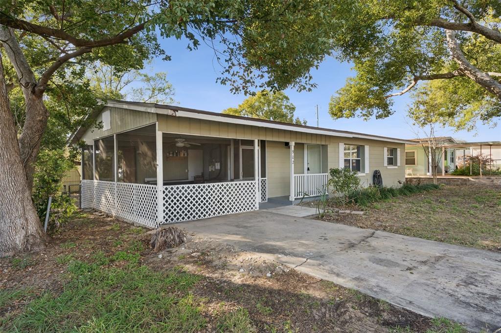 A single-story house with a screened-in porch, concrete driveway, and mature trees in the yard — 902 S GALENA AVENUE, MINNEOLA, FL