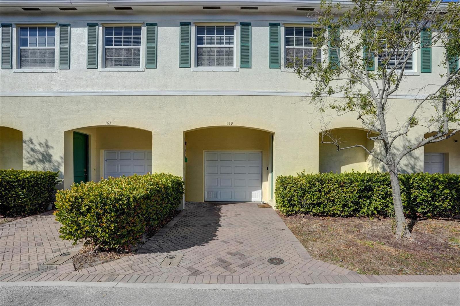 A row of townhouses with beige stucco walls, green shutters, and individual garage bays — 159 SW 7th Court, Pompano Beach FL 33060, POMPANO BEACH, FL