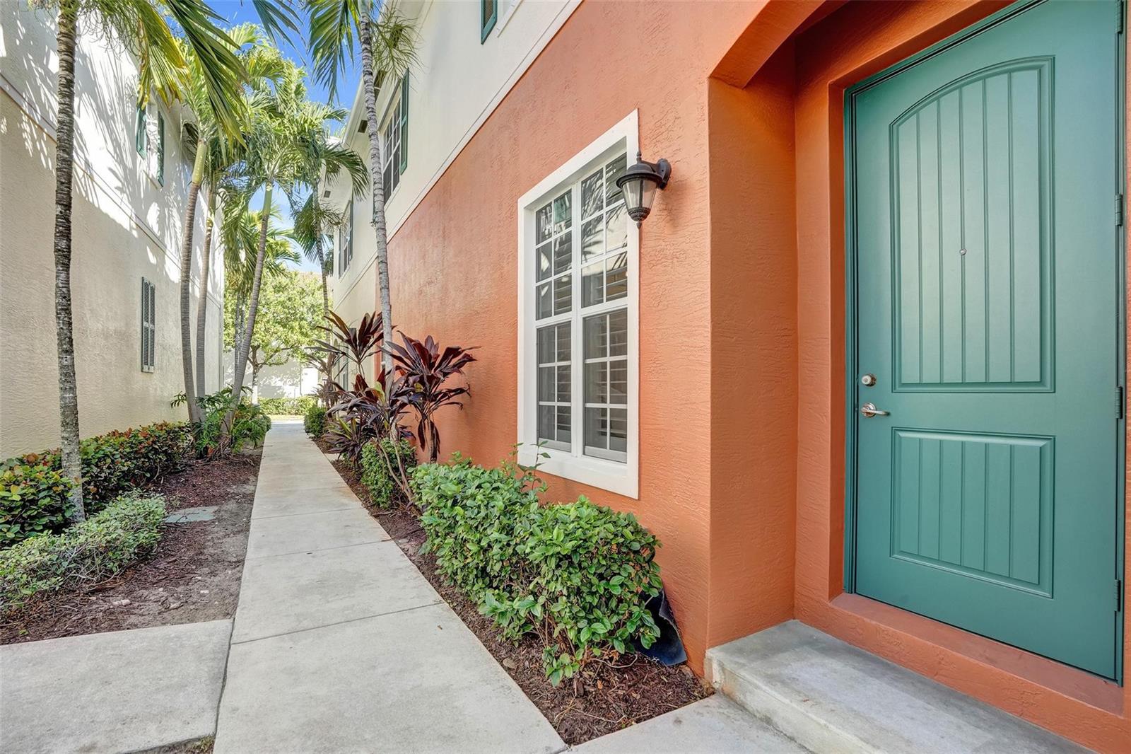 A teal front door sits on an orange exterior wall next to a concrete walkway — 159 SW 7th Court, Pompano Beach FL 33060, POMPANO BEACH, FL