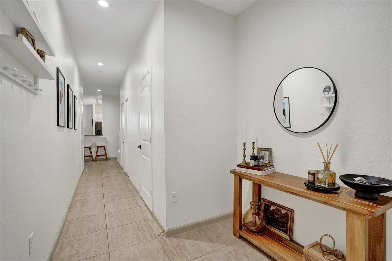 A hallway with tile flooring leads to a kitchen area past a wooden console table — 159 SW 7th Court, Pompano Beach FL 33060, POMPANO BEACH, FL