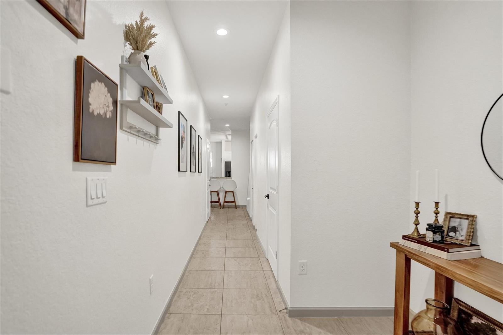 A long hallway with light tile flooring leads toward a kitchen area with bar stools — 159 SW 7th Court, Pompano Beach FL 33060, POMPANO BEACH, FL