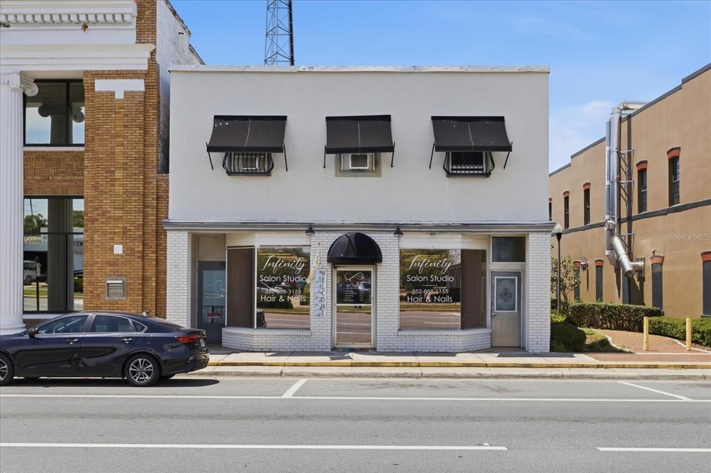 A two-story commercial building with a white facade, black awnings, and a salon storefront — 61 N CENTRAL AVENUE, UMATILLA, FL